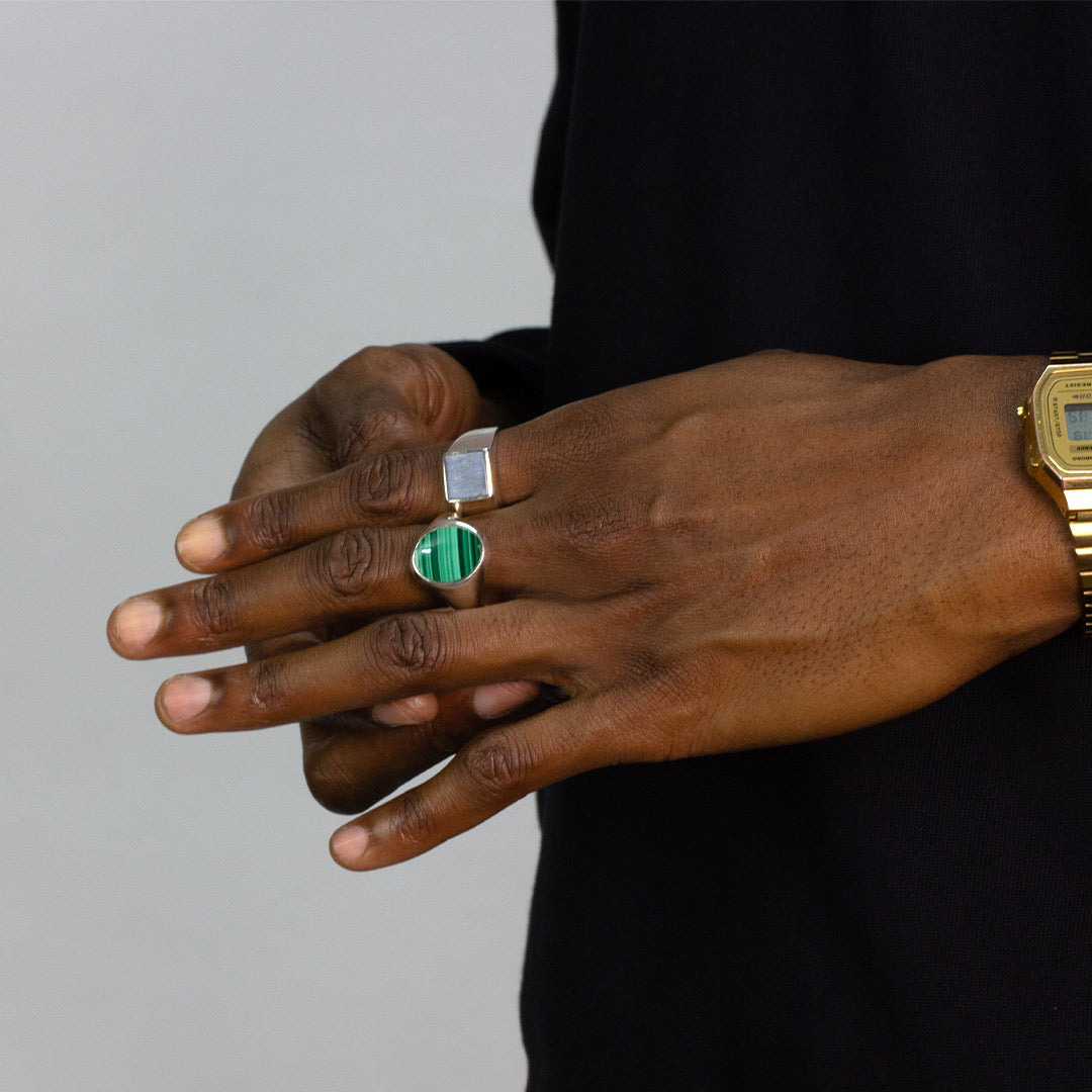 Hand wearing different rings against a plain background