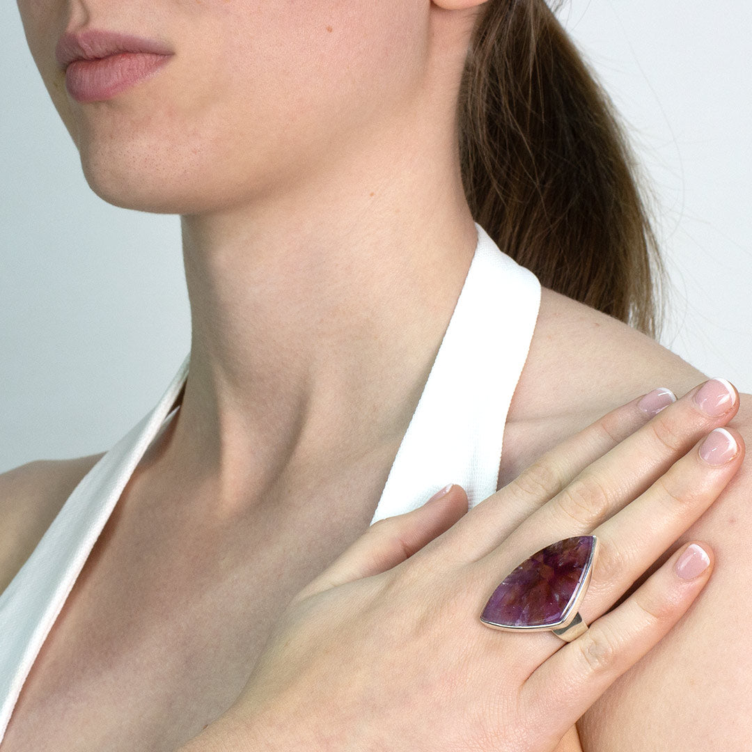 Woman wearing a silver ring with a purple gemstone on a plain background