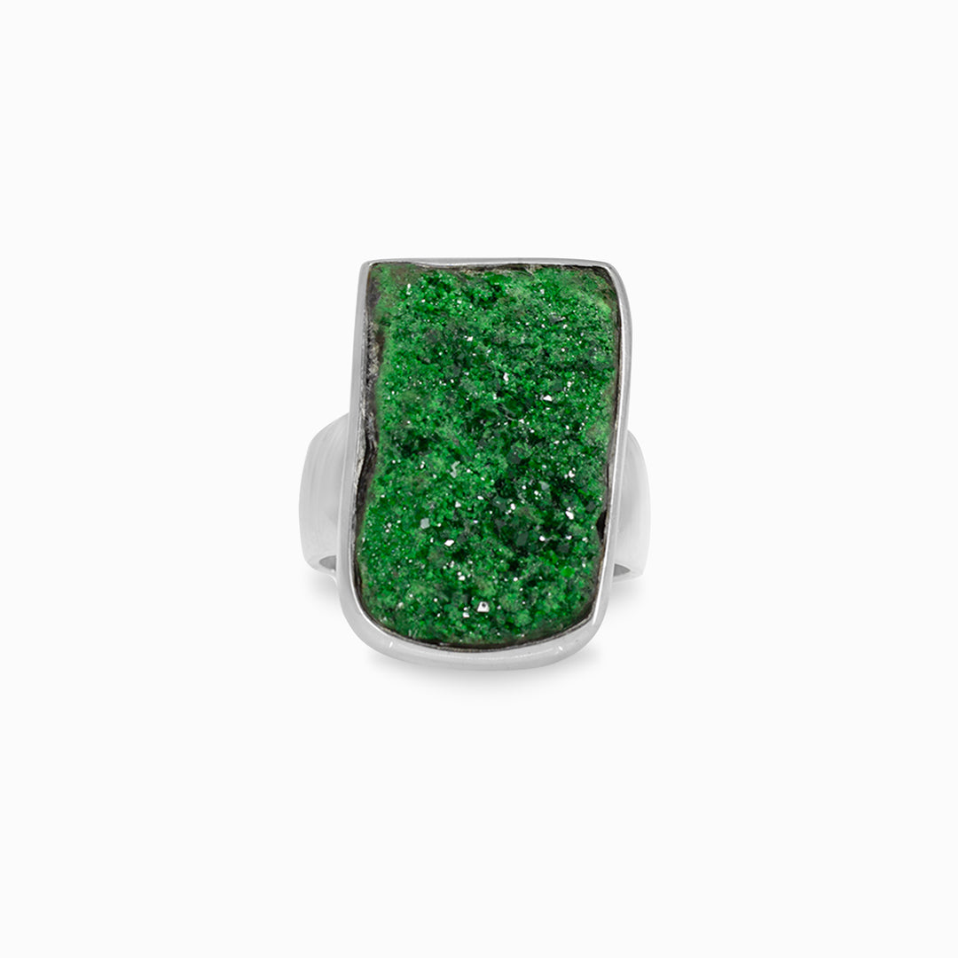 Silver ring with a green raw gemstone on a white background