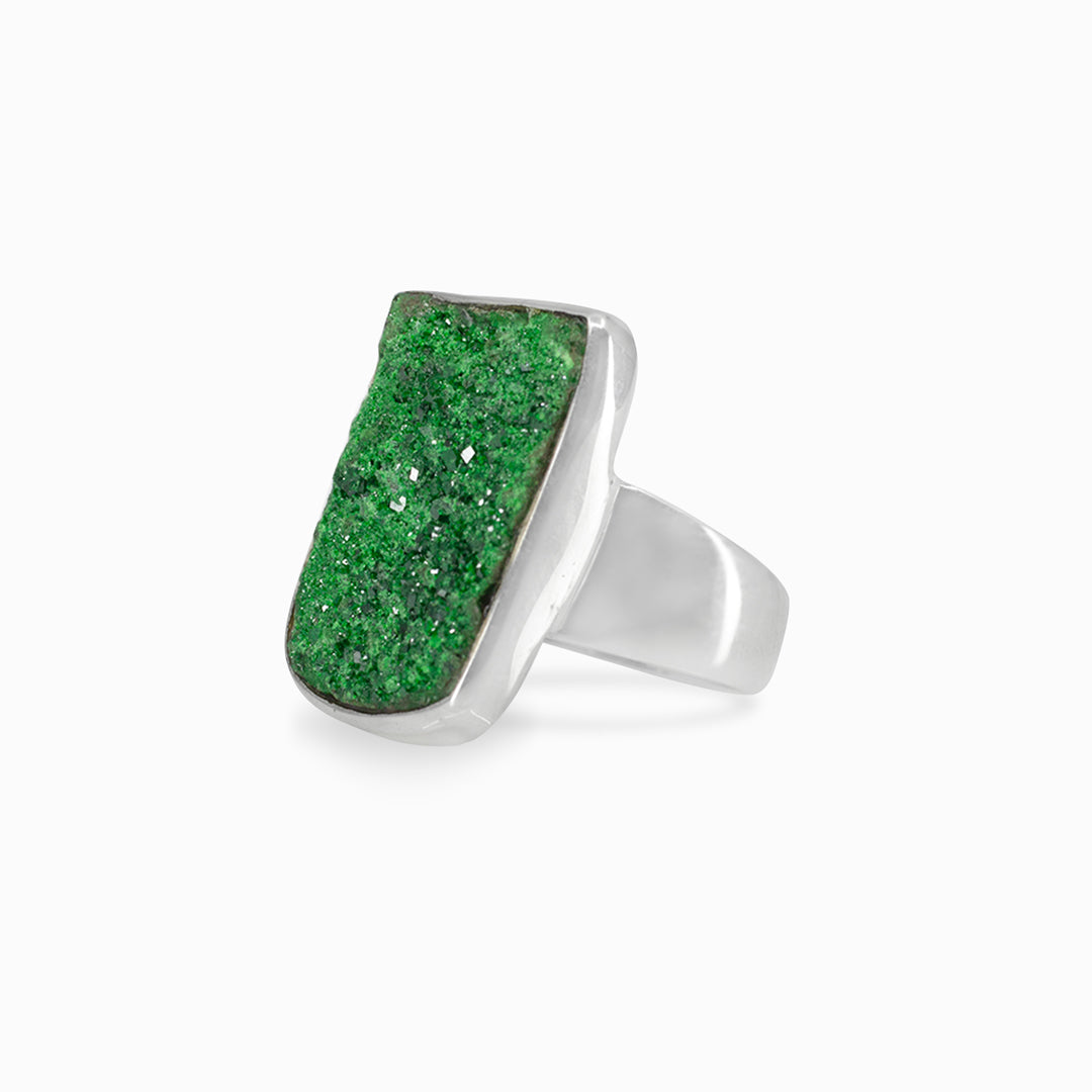Silver ring with a green raw gemstone on a white background