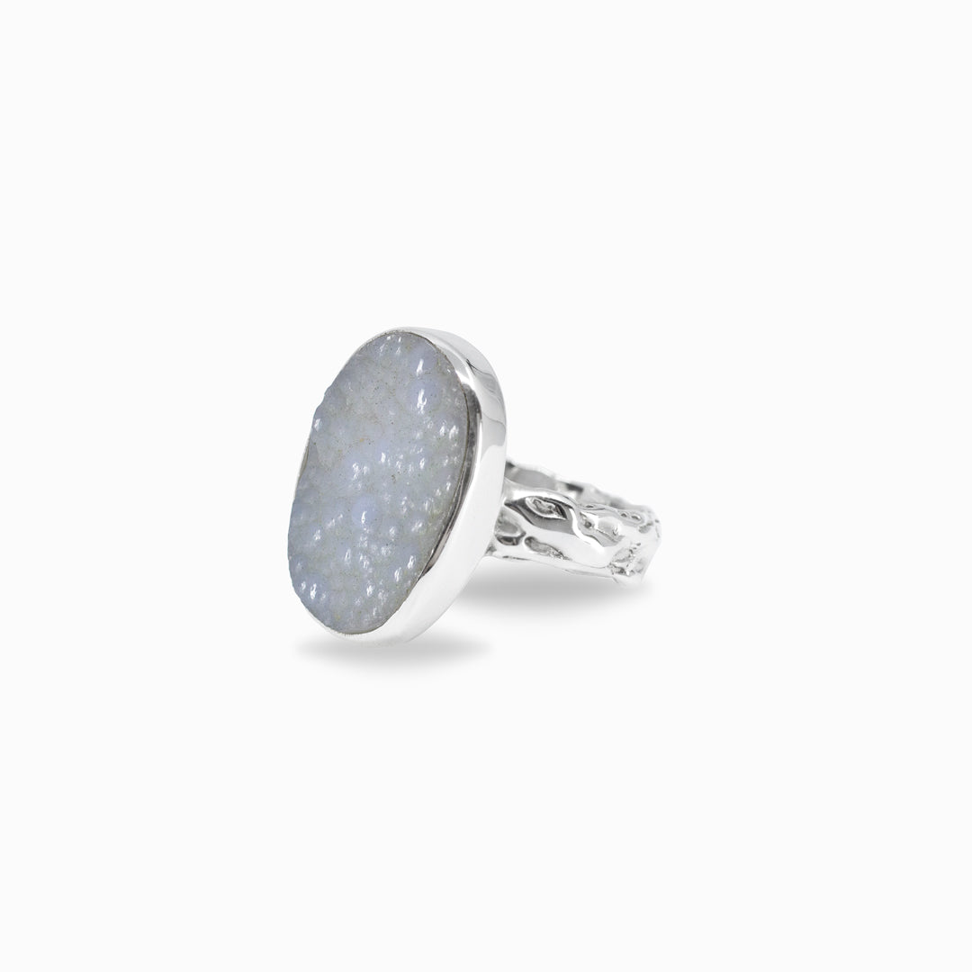 Silver ring with a textured stone and band on a white background