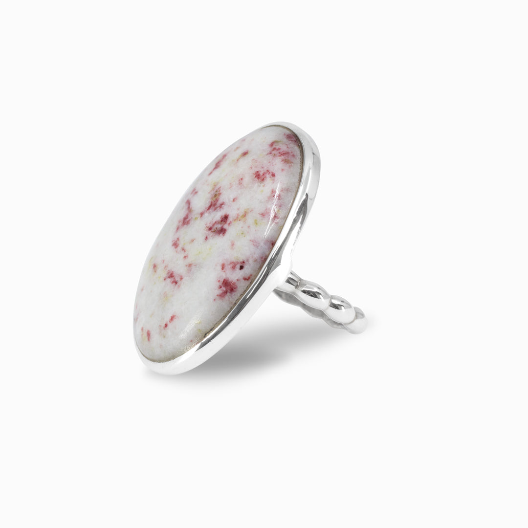 Silver ring with a red speckled white stone on a white background