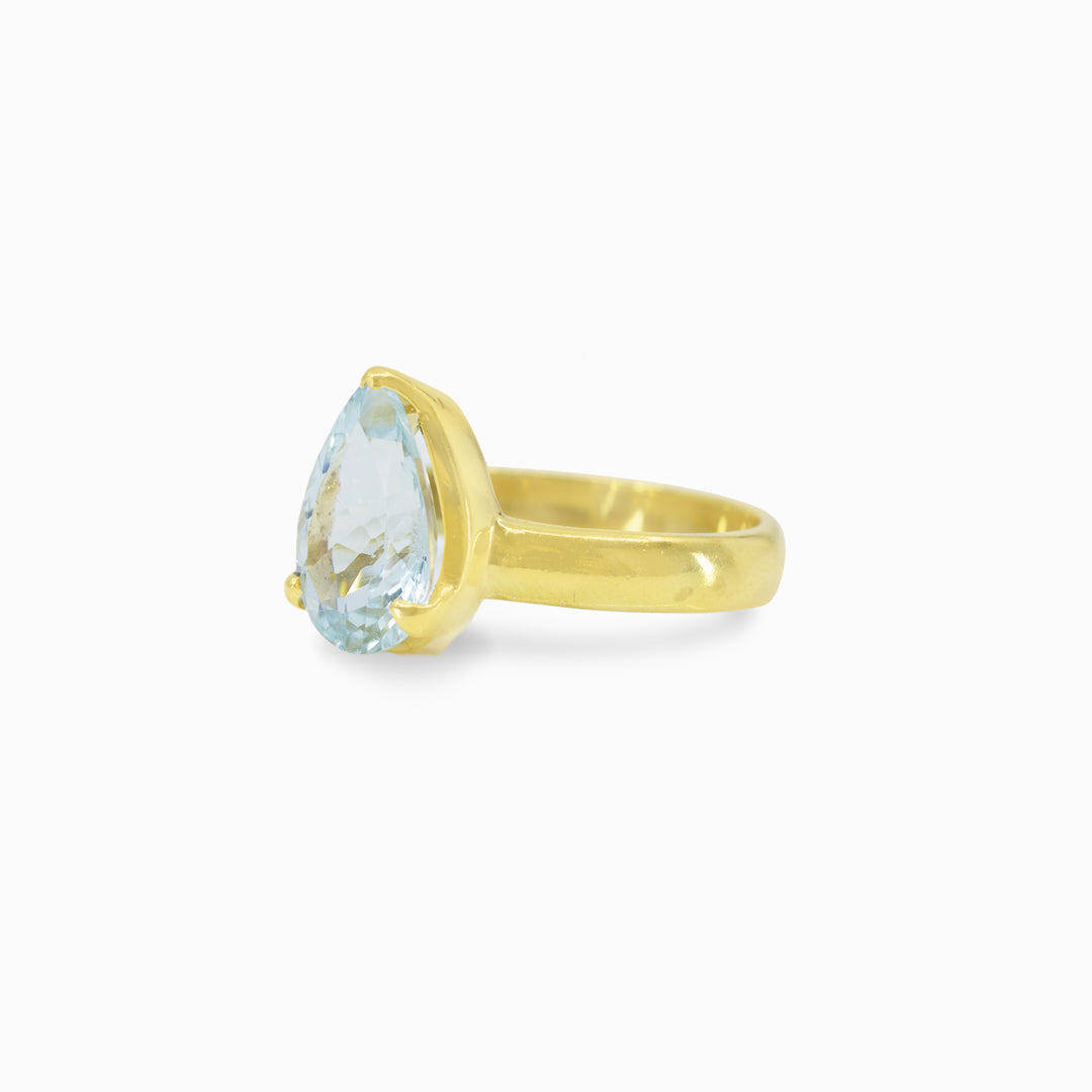 Gold ring with a light blue gemstone on a white background