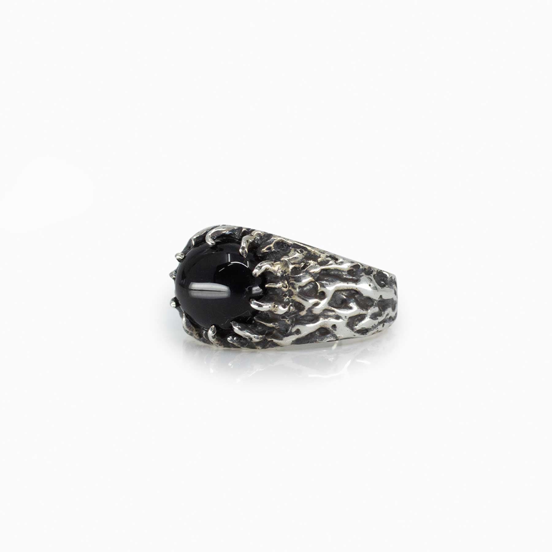 Silver ring with a black gemstone and textured band on a white background