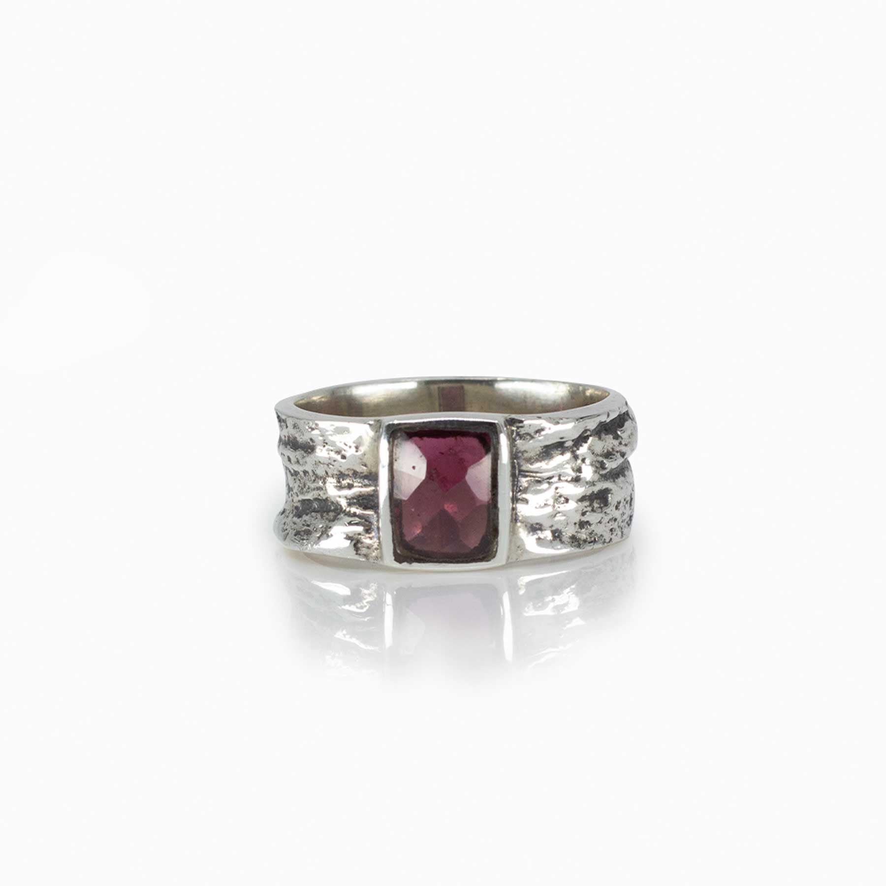 Silver ring with a red gemstone on a white background