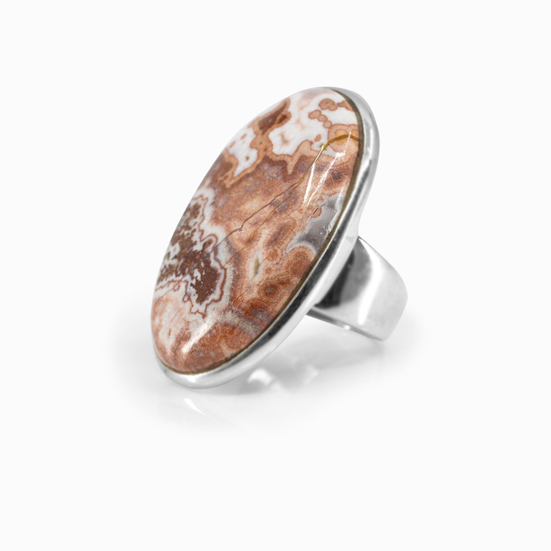 Silver ring with an oval stone with brown, orange and white patterns on a white background