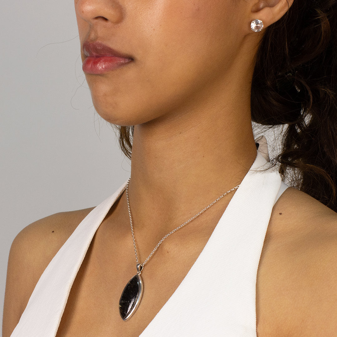 Woman wearing a black marquise necklace against a plain background