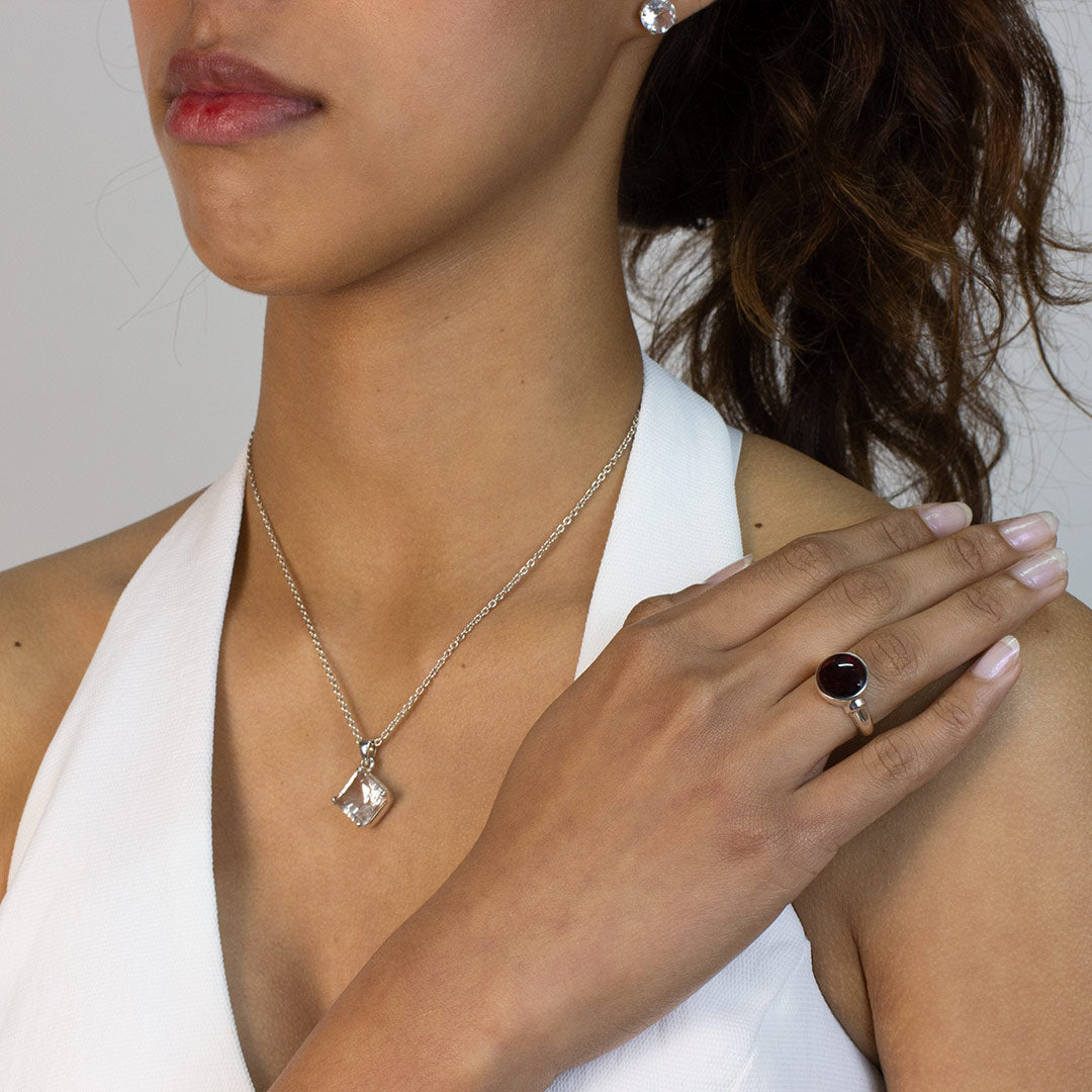 Woman wearing a silver ring with a red gemstone on a plain background