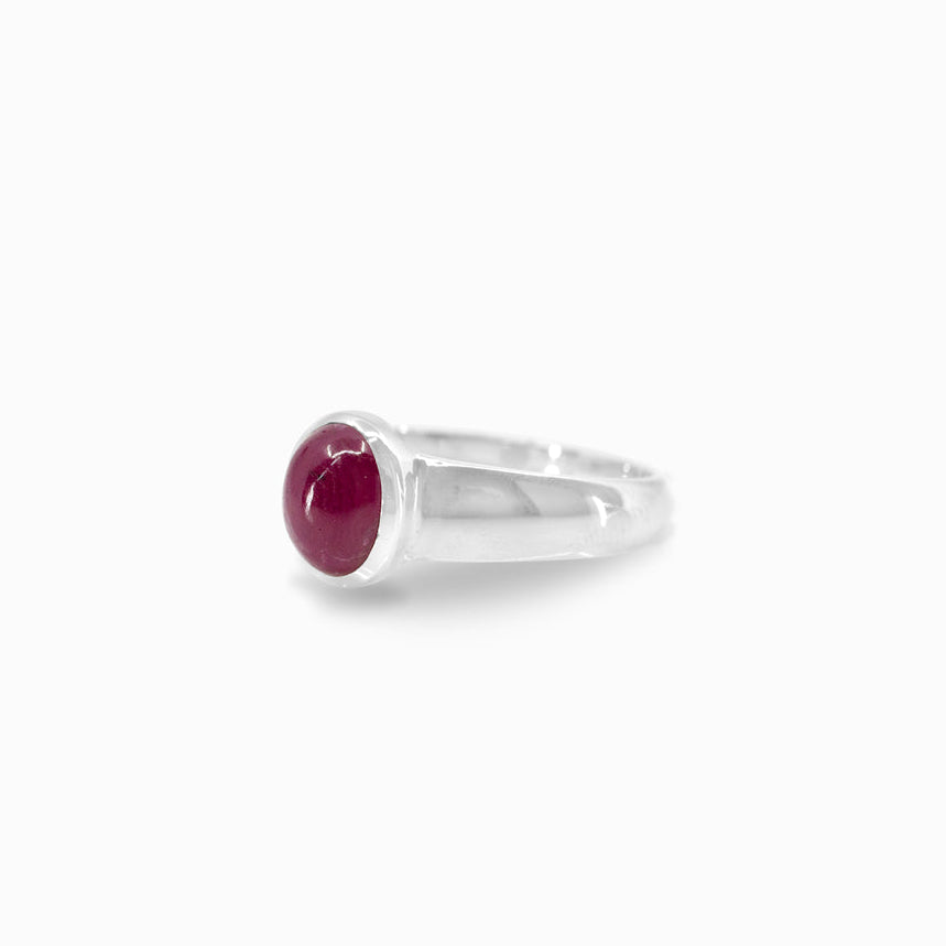 Silver ring with a red gemstone on a white background