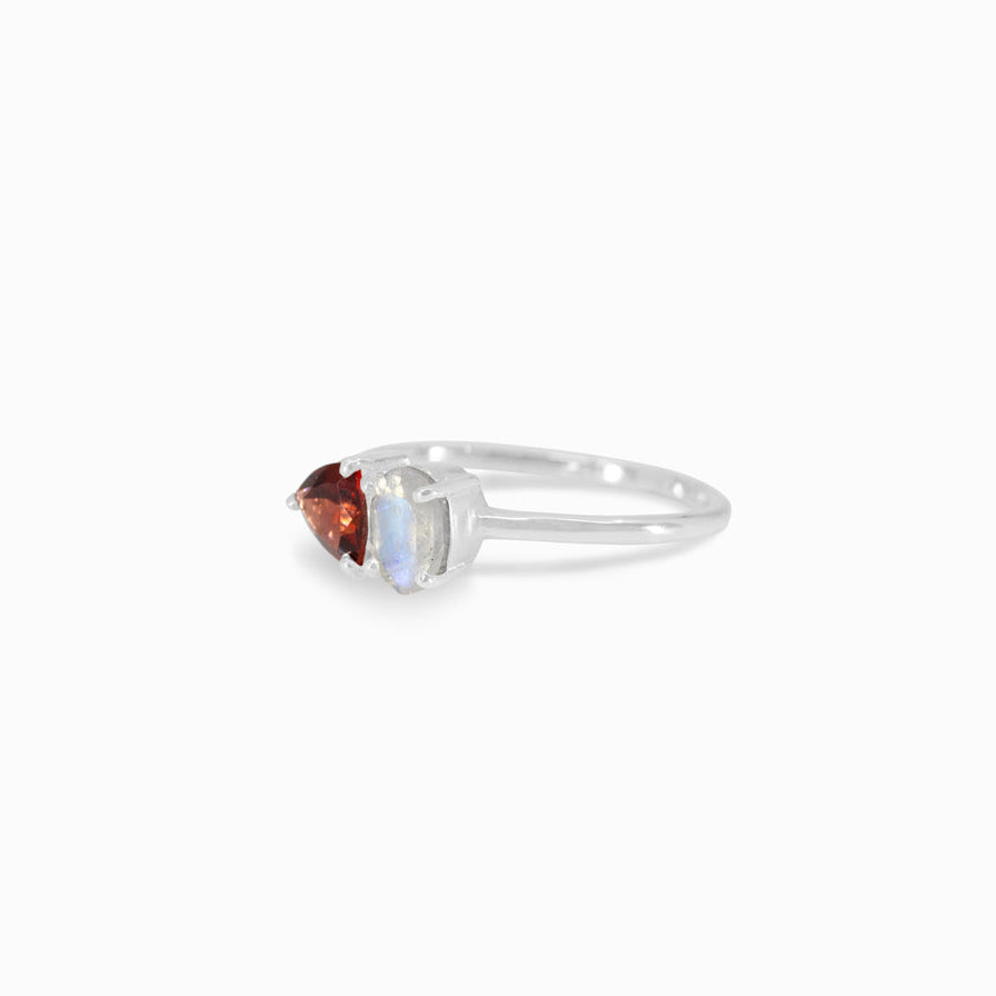 Silver ring with red and clear gemstones on a white background