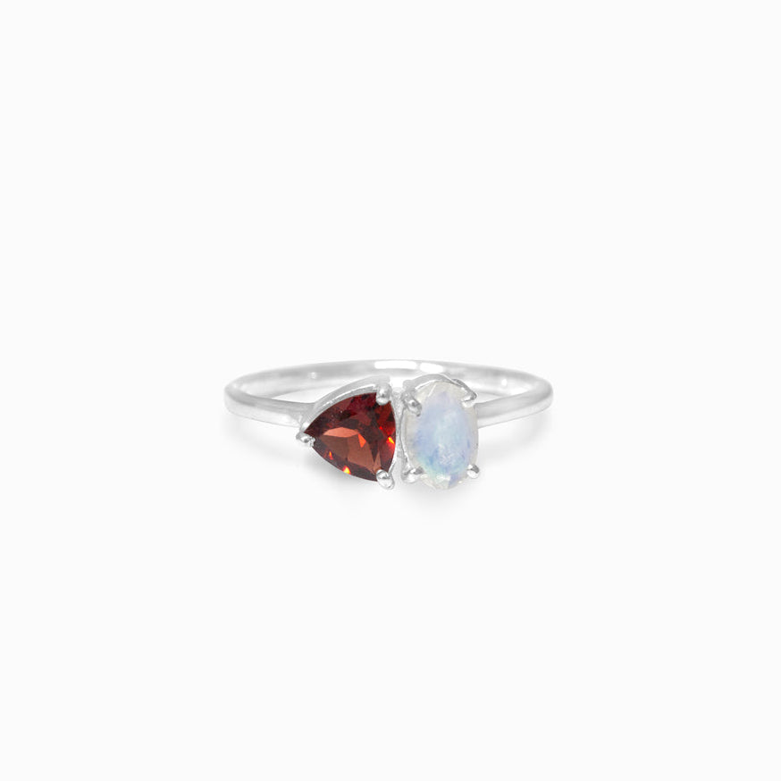 Silver ring with red and clear gemstones on a white background