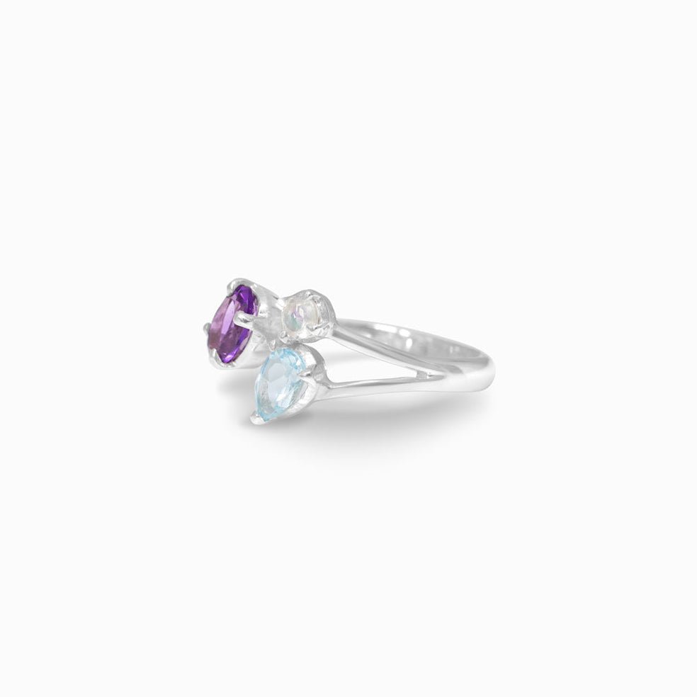 Silver ring with purple, blue and clear gemstones on a white background