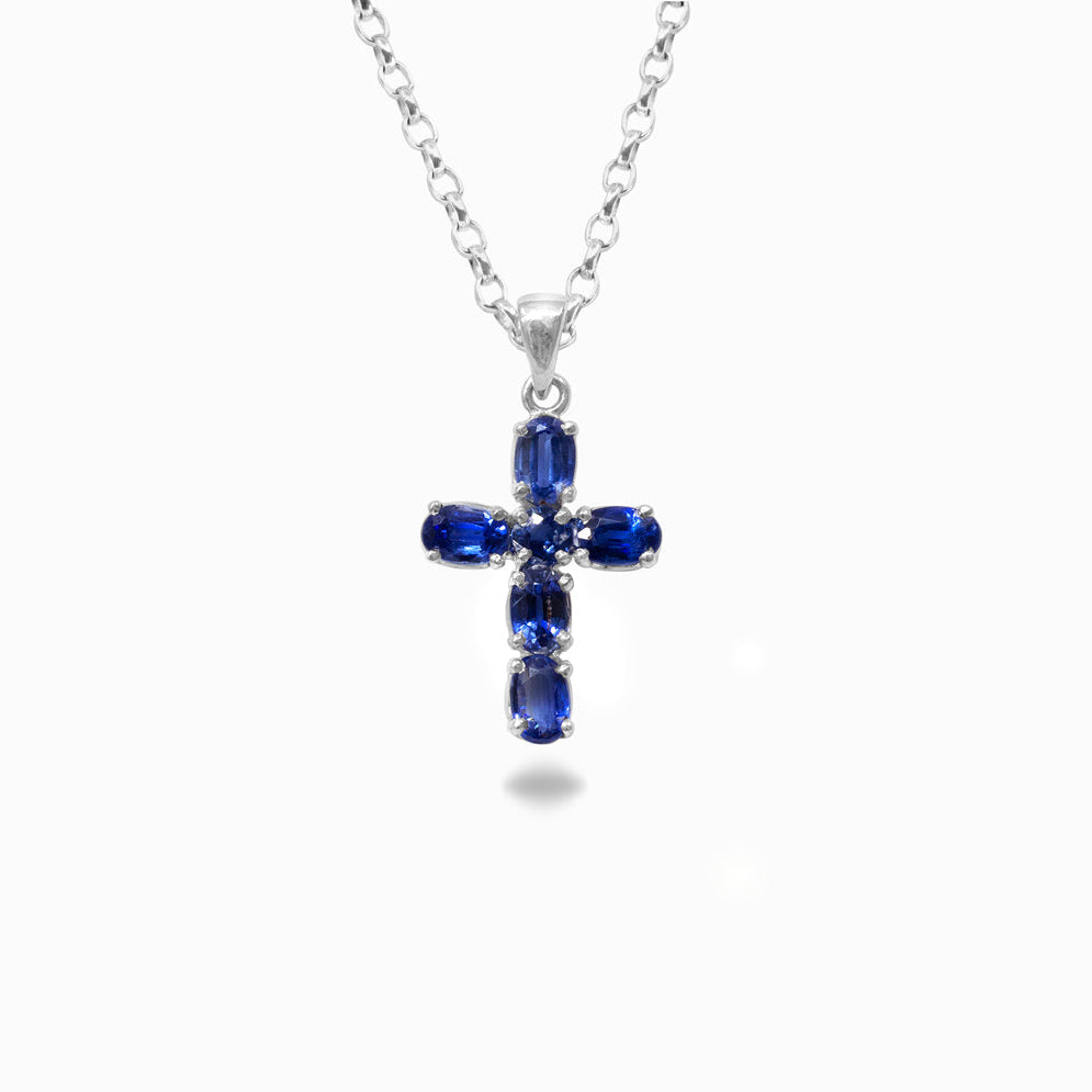 Silver cross pendant with blue gemstones on a white background