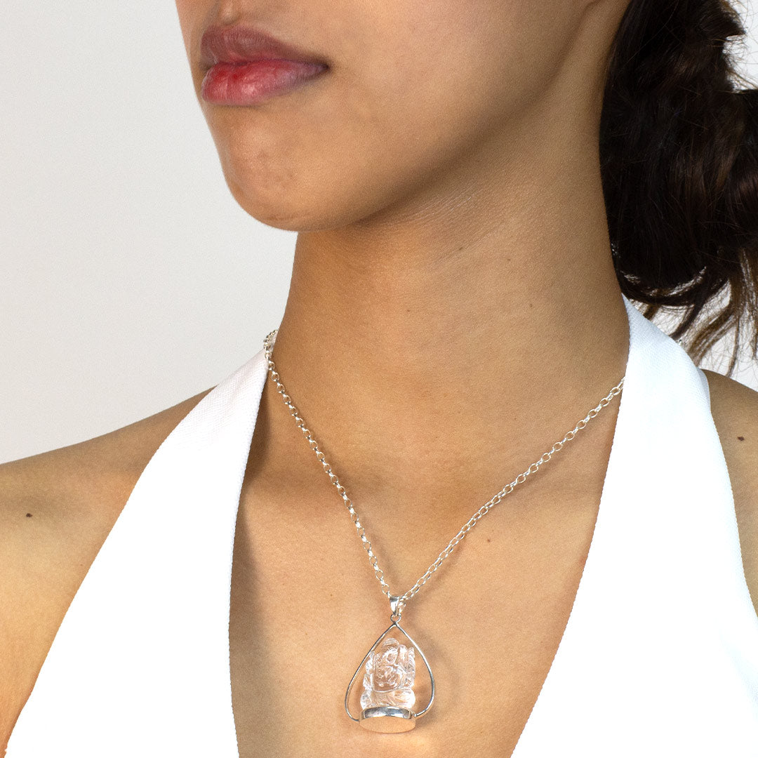 Woman wearing a silver pendant with a clear stone on a plain background
