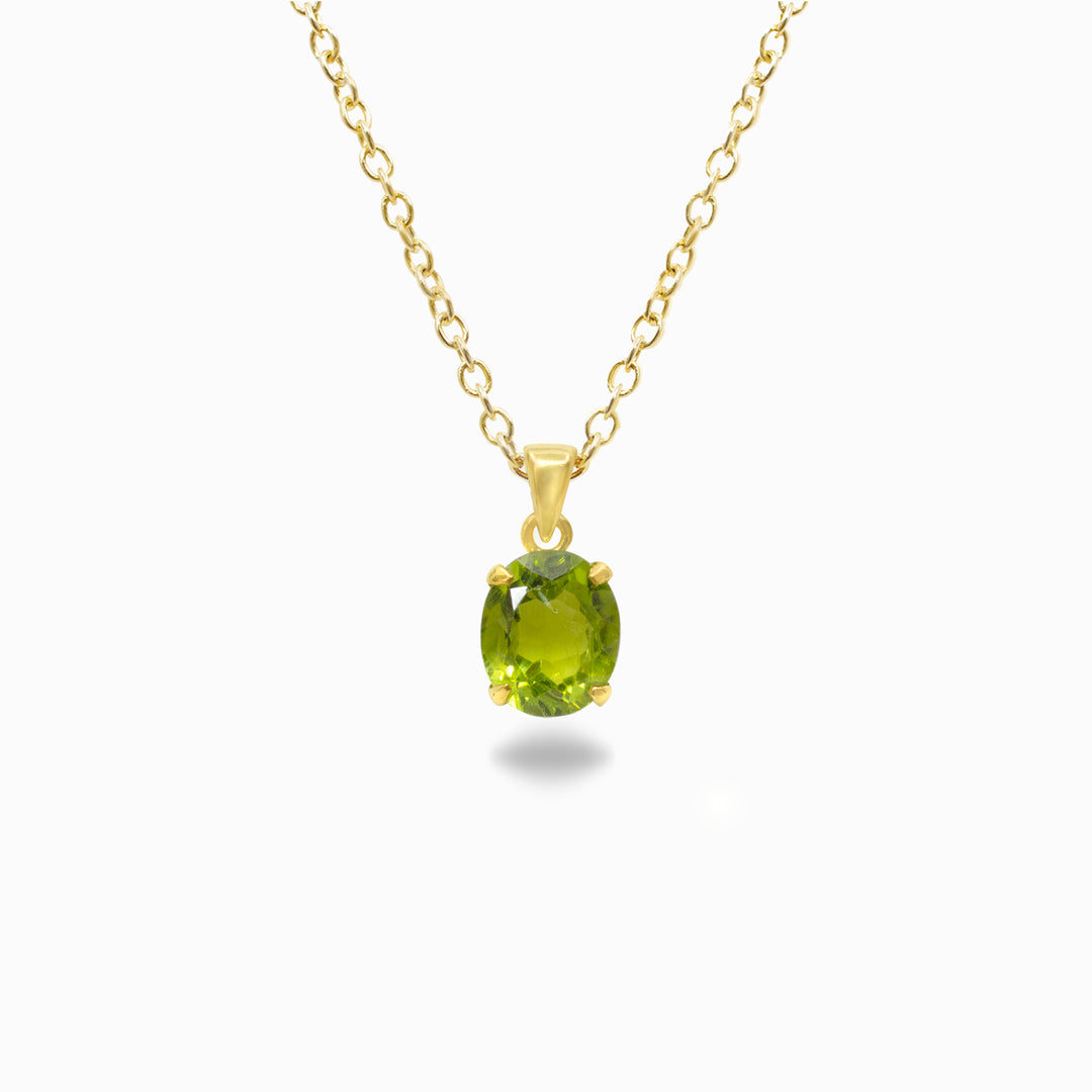 Gold necklace with a green gemstone pendant on a white background