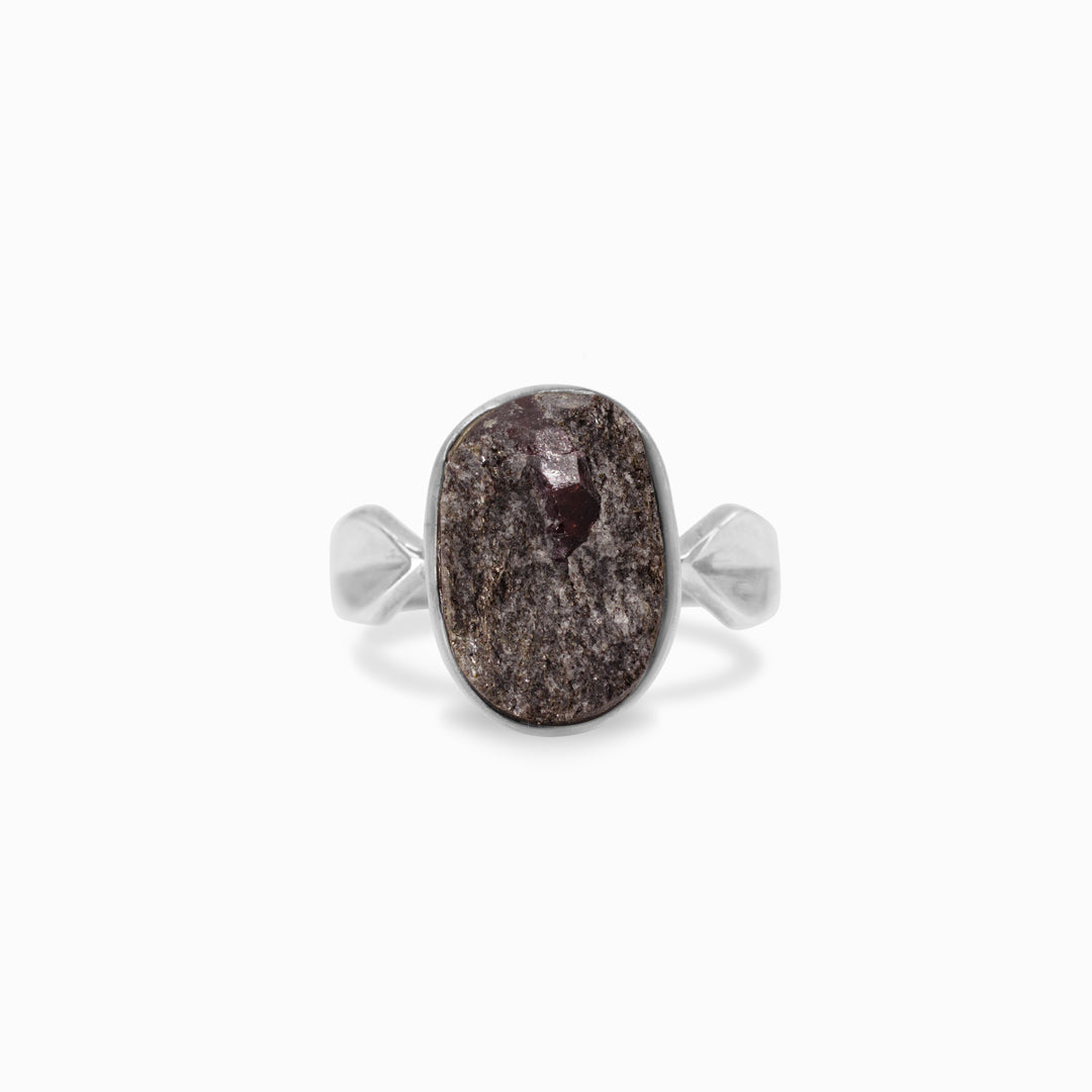 Silver ring with a rough red stone on a white background