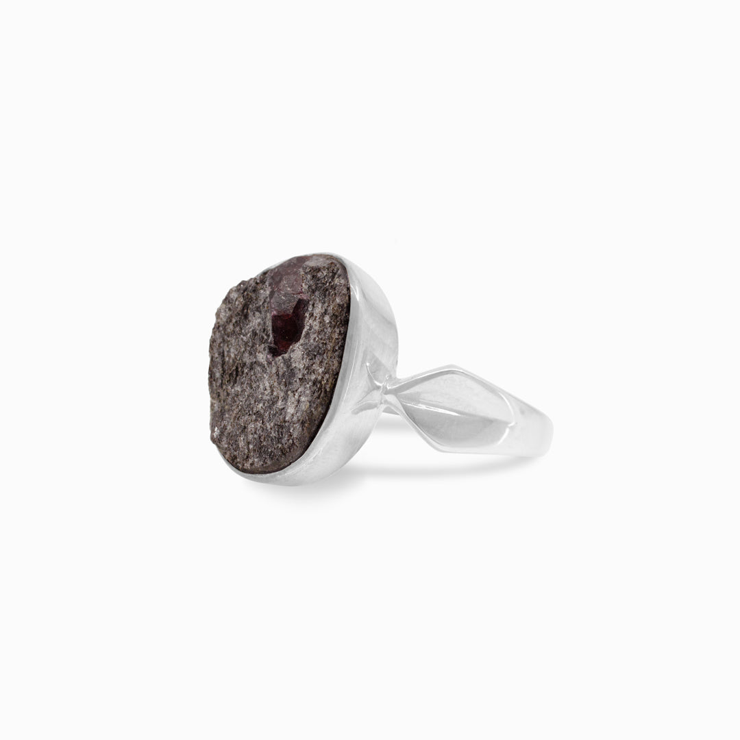 Silver ring with a rough red stone on a white background
