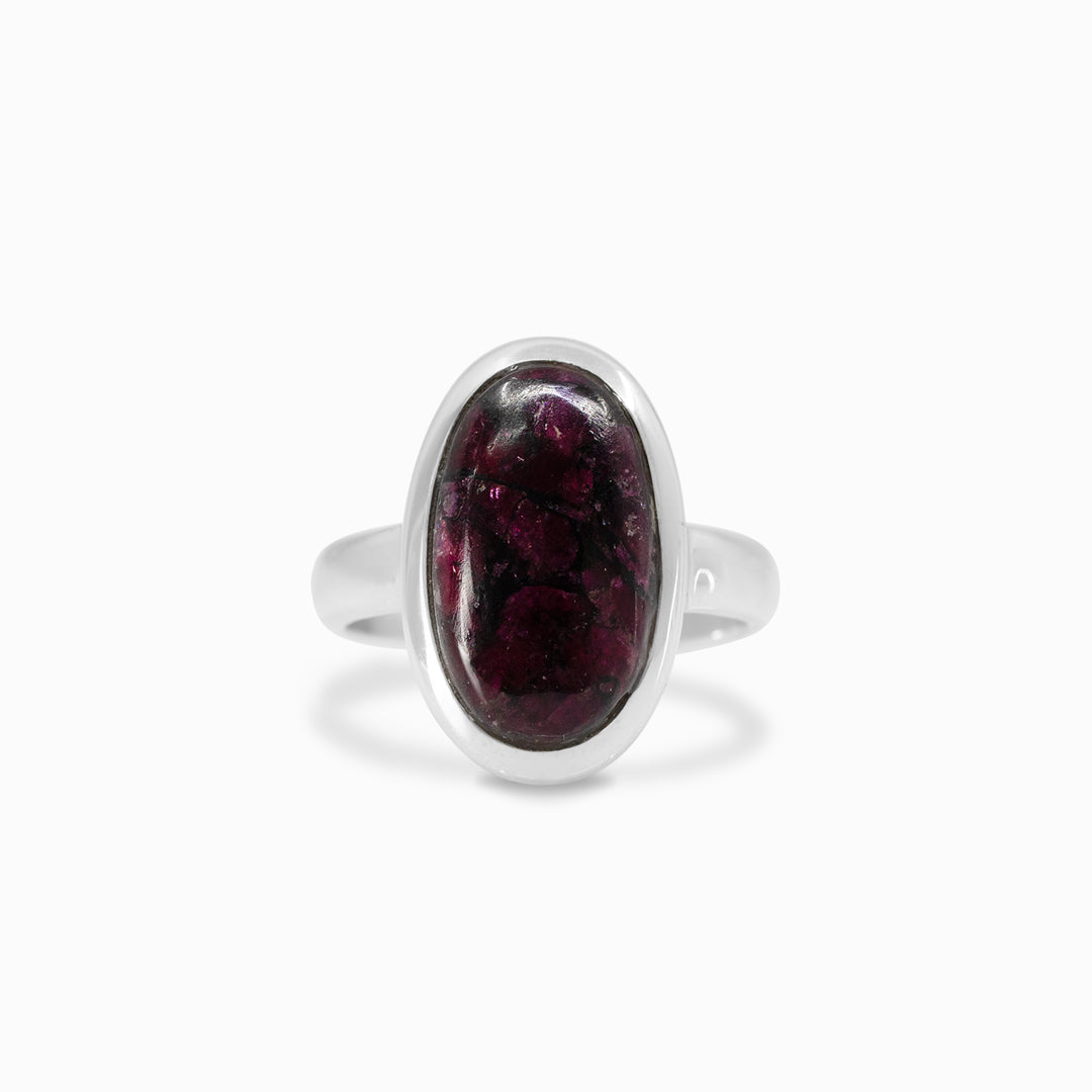 Silver ring with a dark pink gemstone on a white background