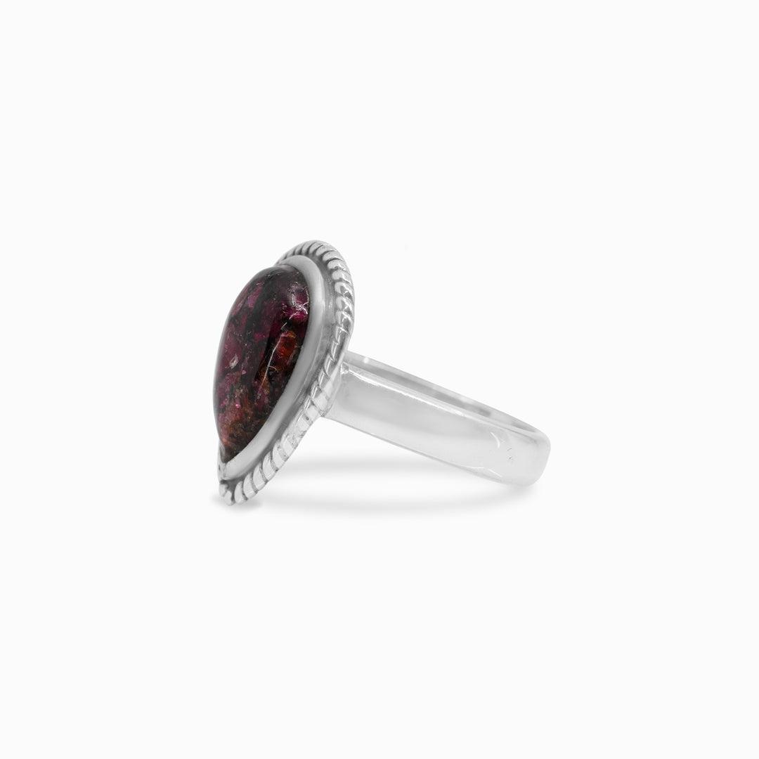 Silver ring with a dark pink gemstone on a white background