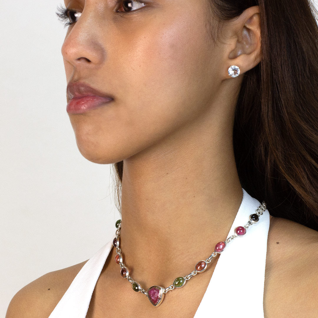 Woman wearing a silver necklace with multicolored gemstones on a white background