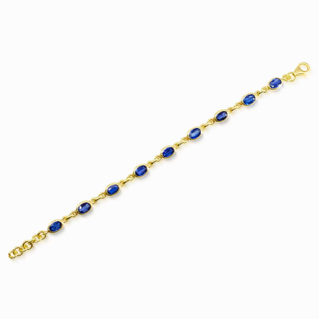 Gold bracelet with blue stones on a white background