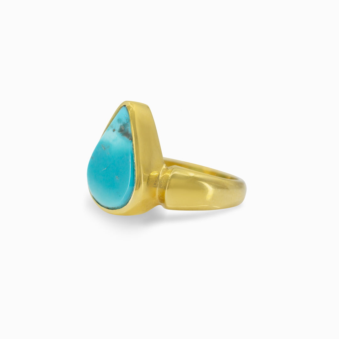 Golden ring with a turquoise teardrop-shaped stone on a white background