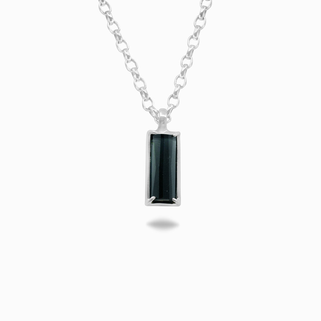Silver necklace with a dark blue gemstone pendant on a white background