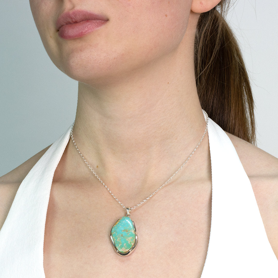 Woman wearing a Turquoise pendant necklace against a neutral background