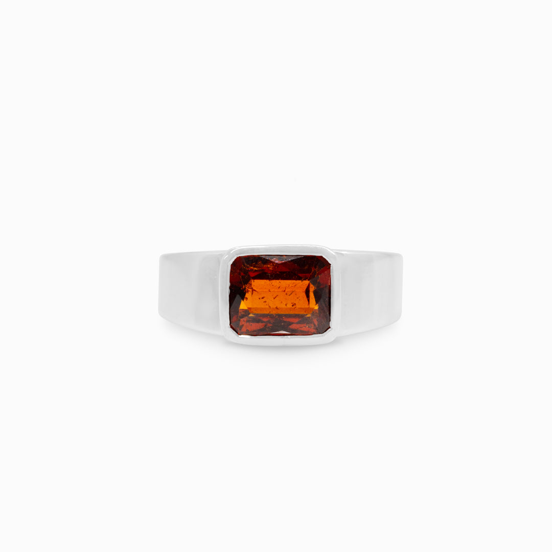 Silver ring with a red gemstone on a white background.