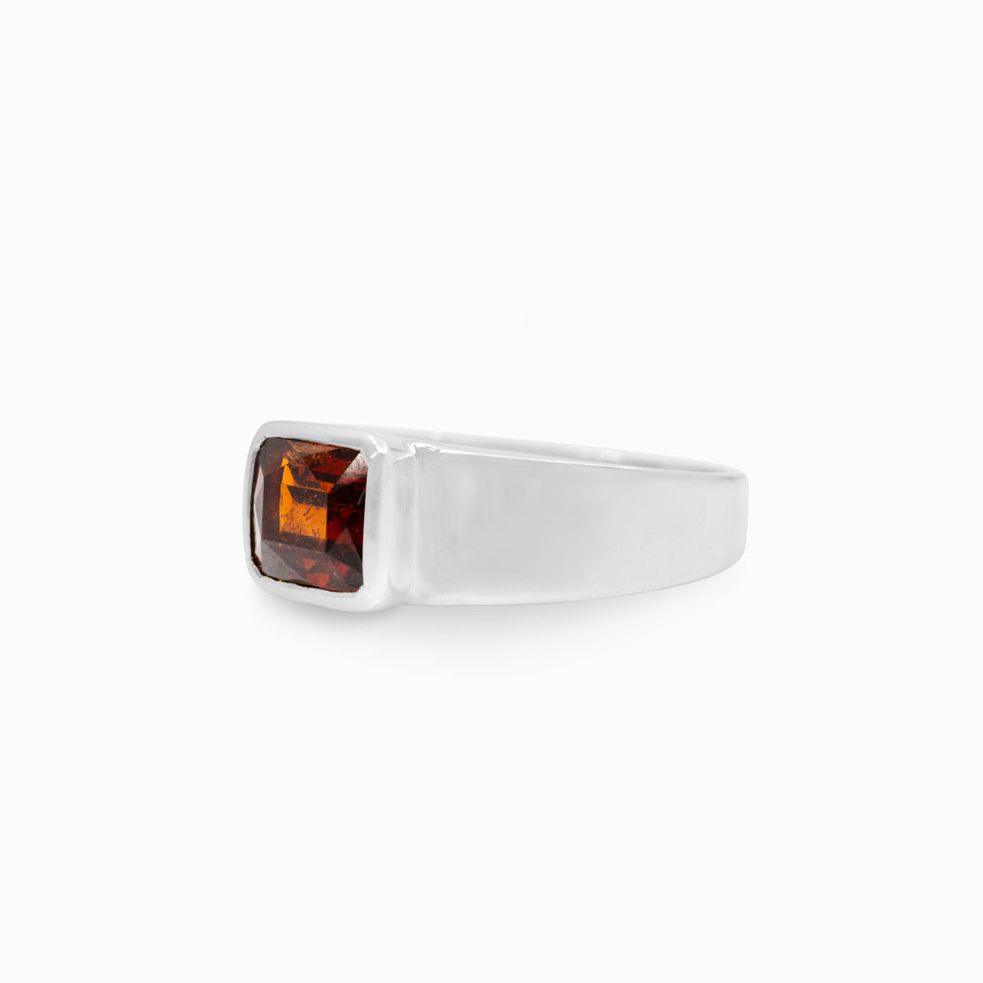 Silver ring with a red gemstone on a white background.