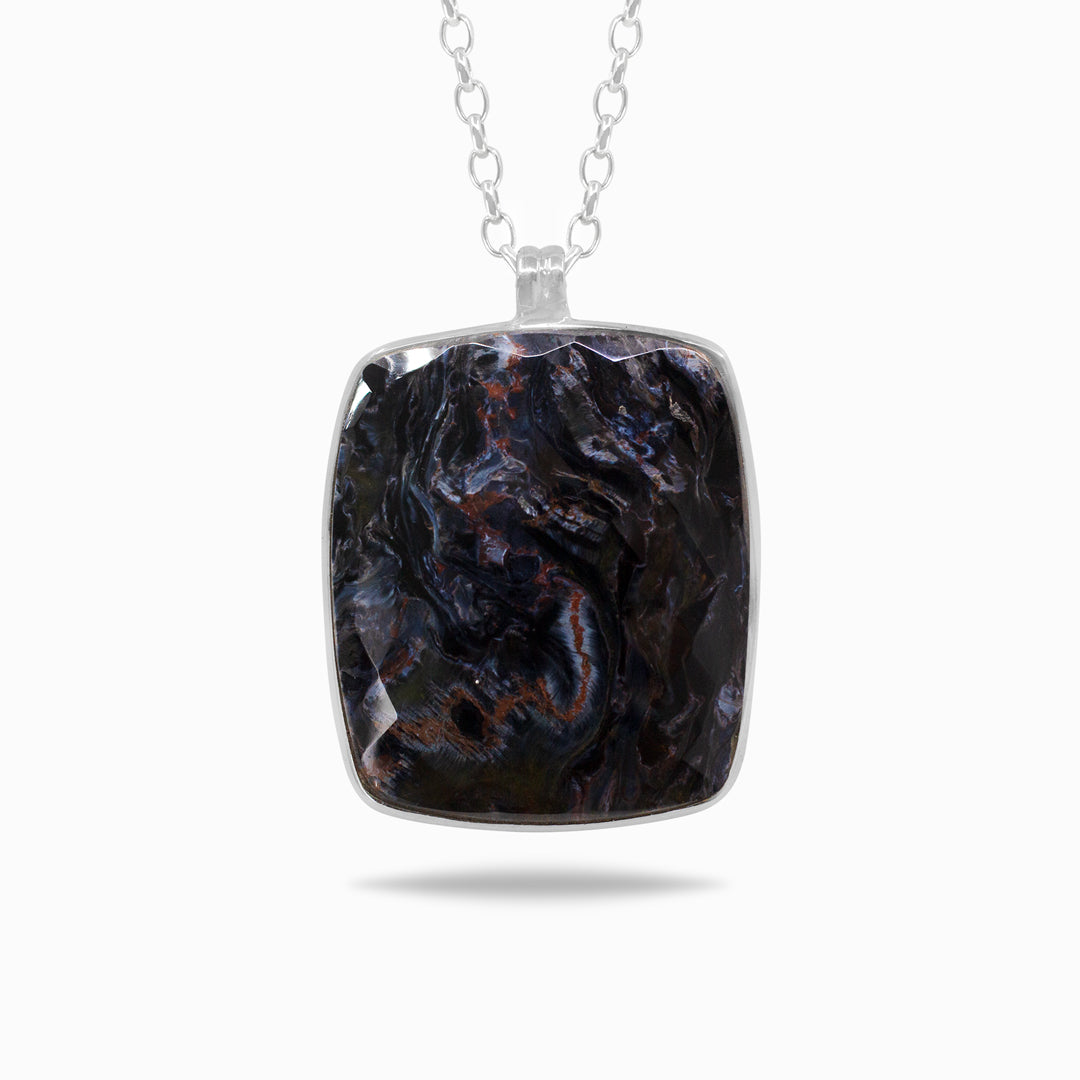 Silver necklace with a dark blue stone on a white background.