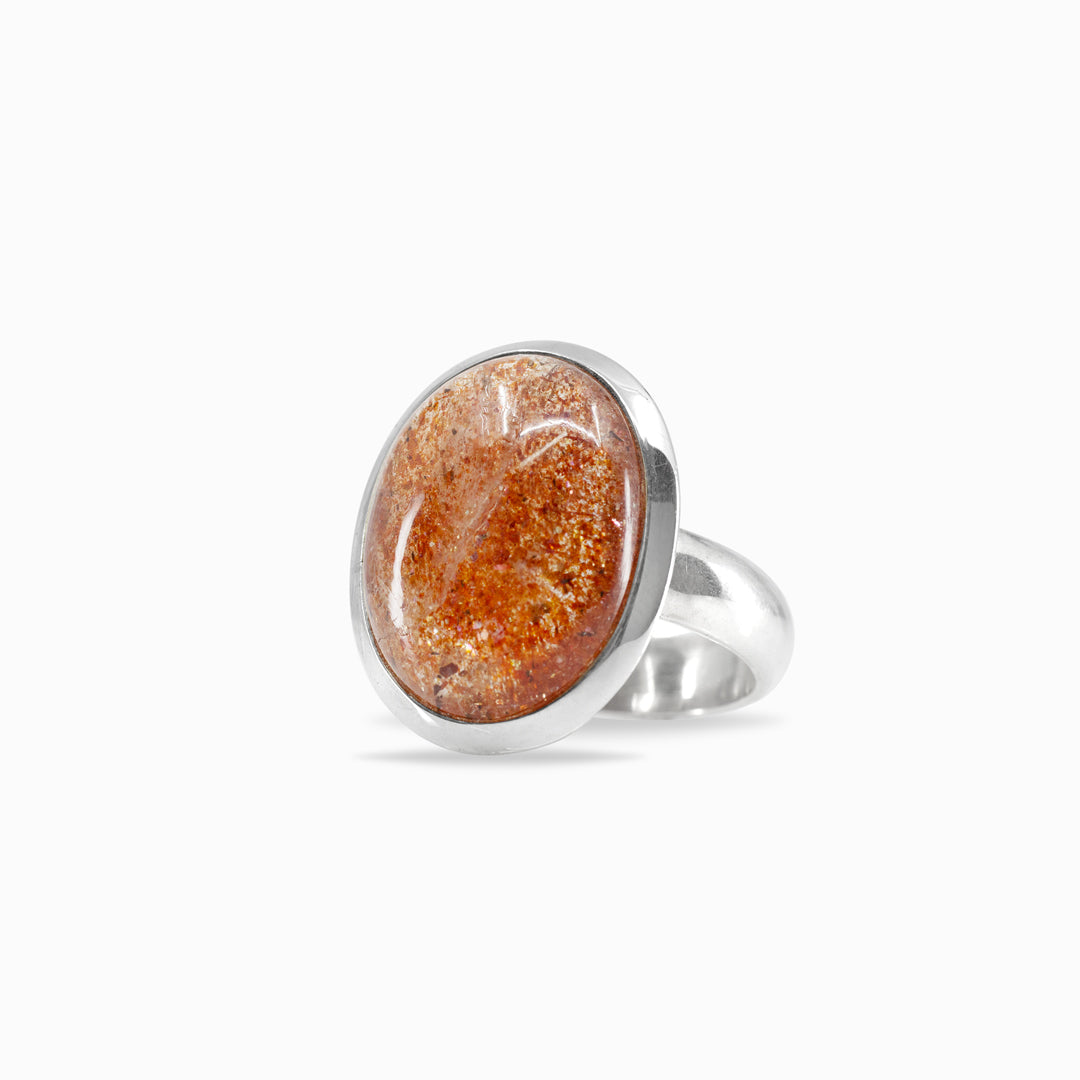 Silver ring with an oval orange gemstone on a white background