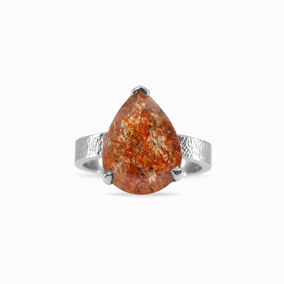 Silver ring with a teardrop-shaped orange gemstone on a white background